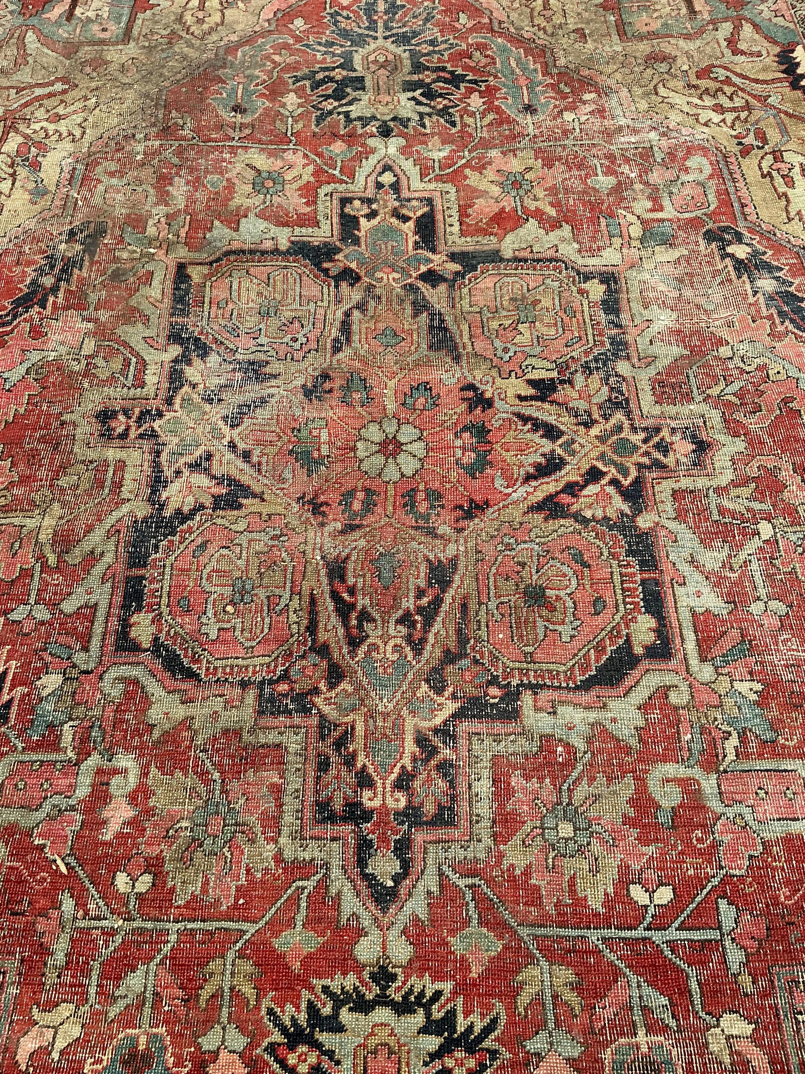 An antique Heriz pink ground carpet, worn and lacking a piece to one corner, 365 x 255cm